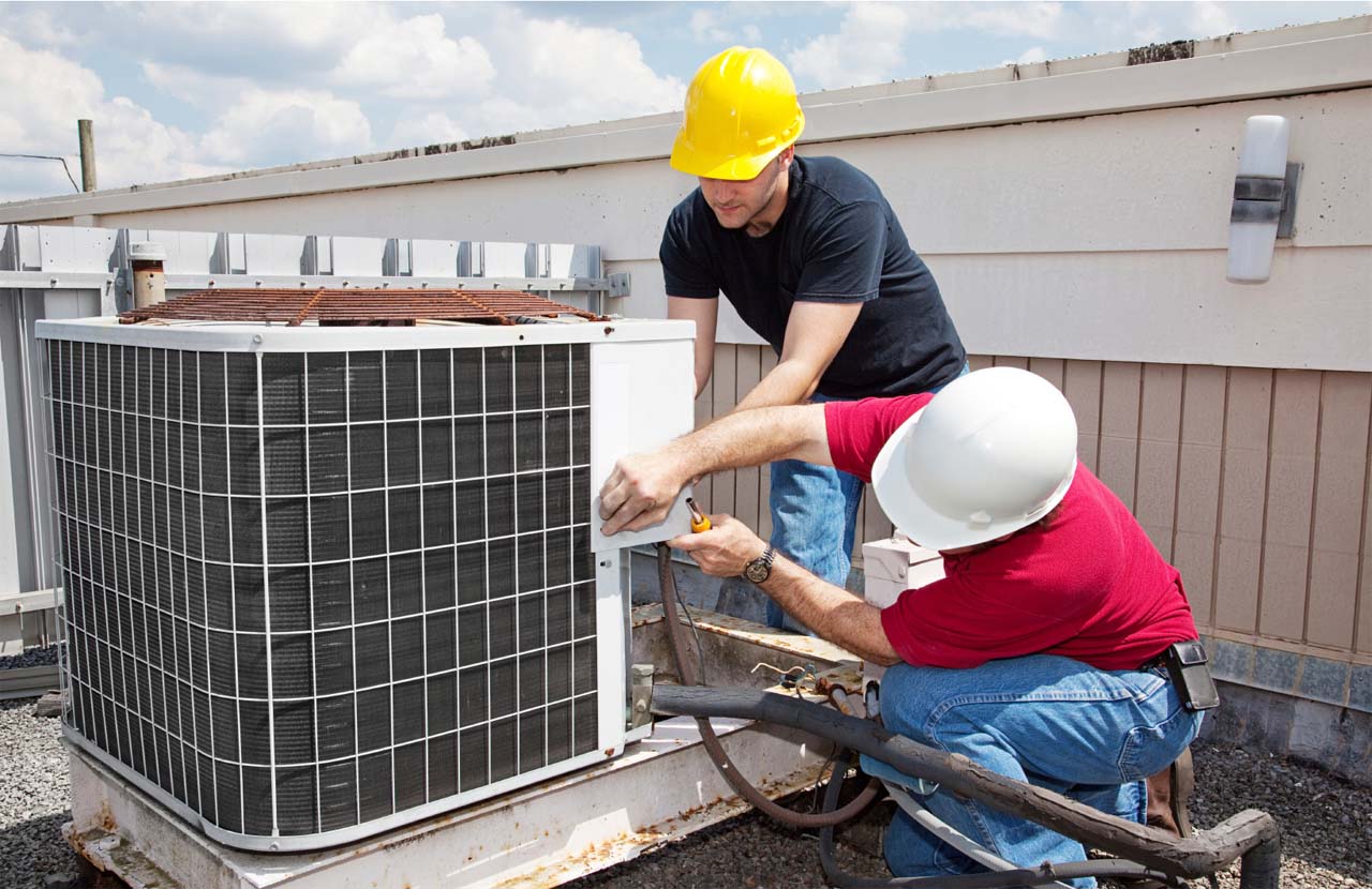 Technicians servicing a commercial rooftop HVAC unit
