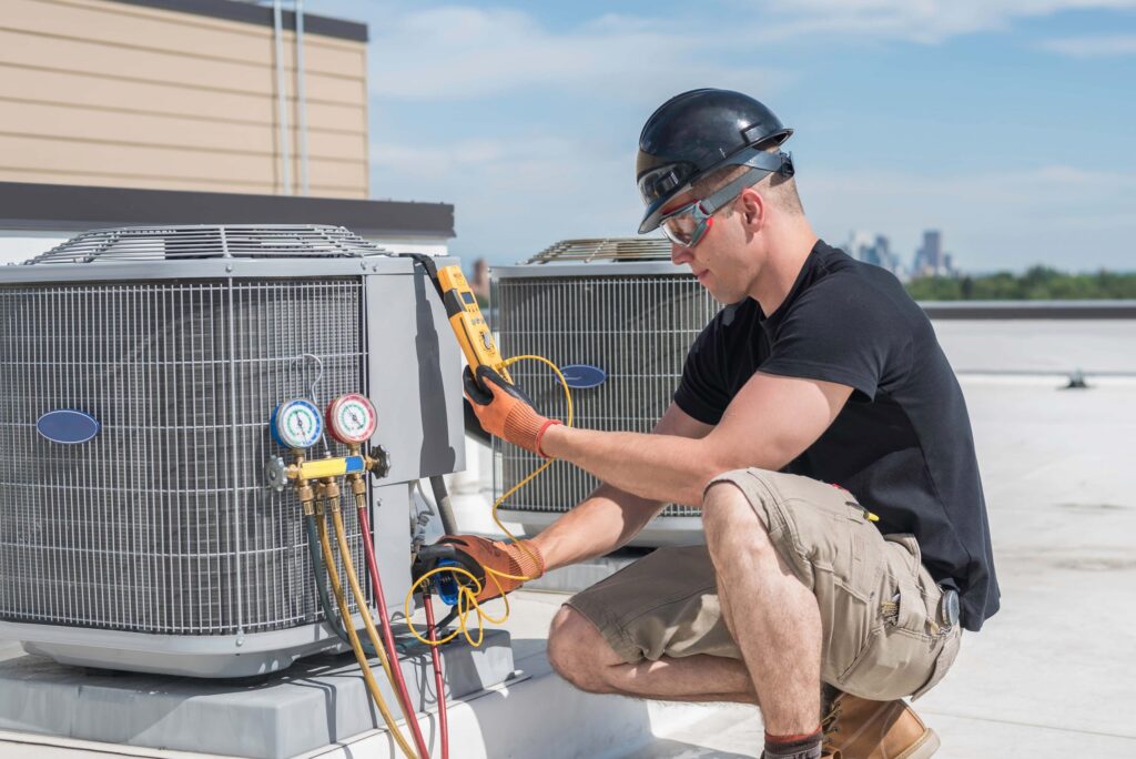HVAC technician testing a rooftop air conditioning unit with gauges
